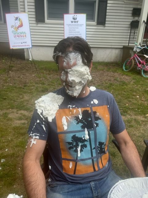 A man wearing a shirt with palm trees on it is covered in whipped cream