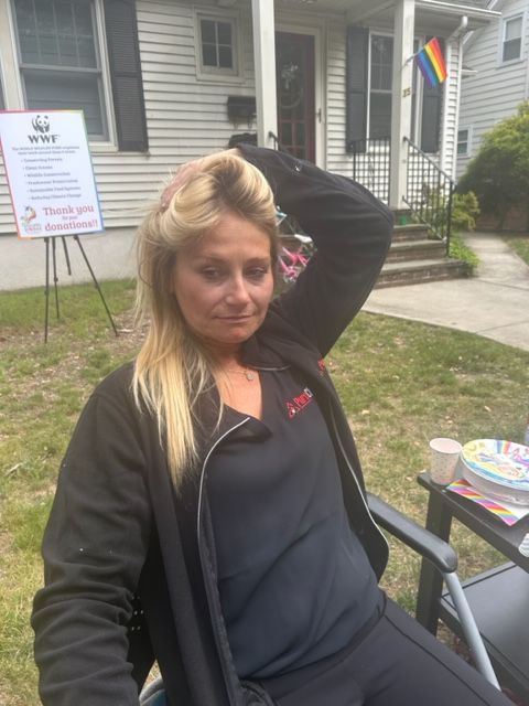 A woman is sitting in a chair in front of a house.