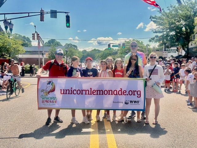 A group of people holding a banner that says unicornlemonade.org