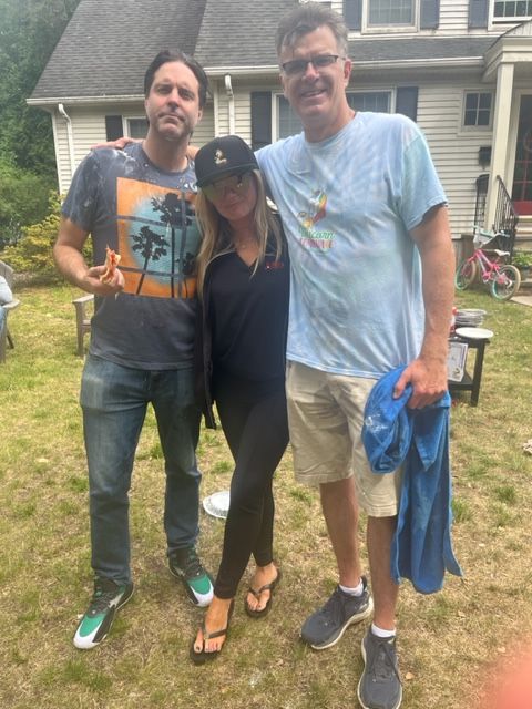 Three people posing for a picture in front of a house