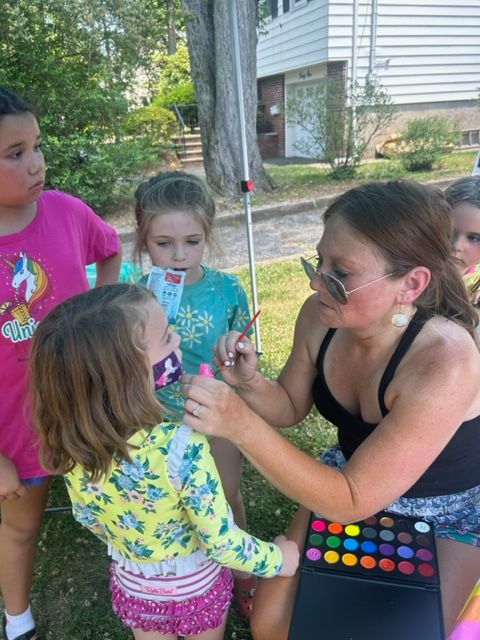 A woman is applying makeup to a little girl 's face.