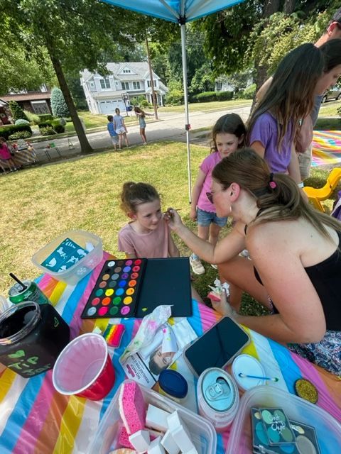 A woman is applying makeup to a little girl 's face