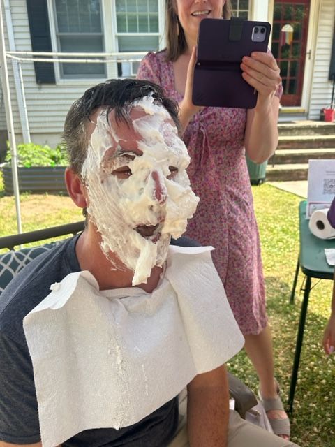 A woman is taking a picture of a man with whipped cream on his face