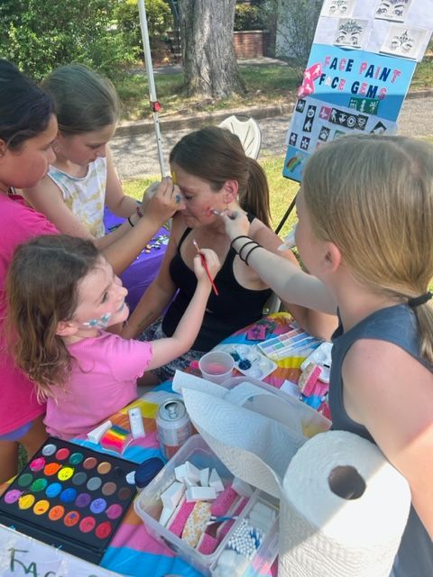 A group of young girls are getting their faces painted