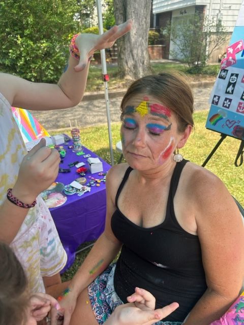 A woman is getting her face painted by a child