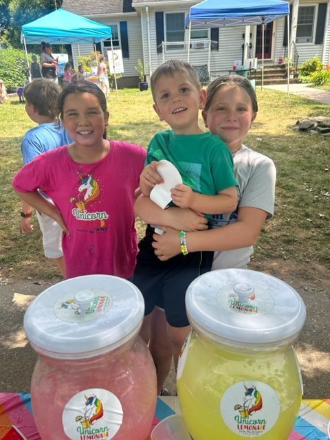 Three children are standing next to jars of ice cream.