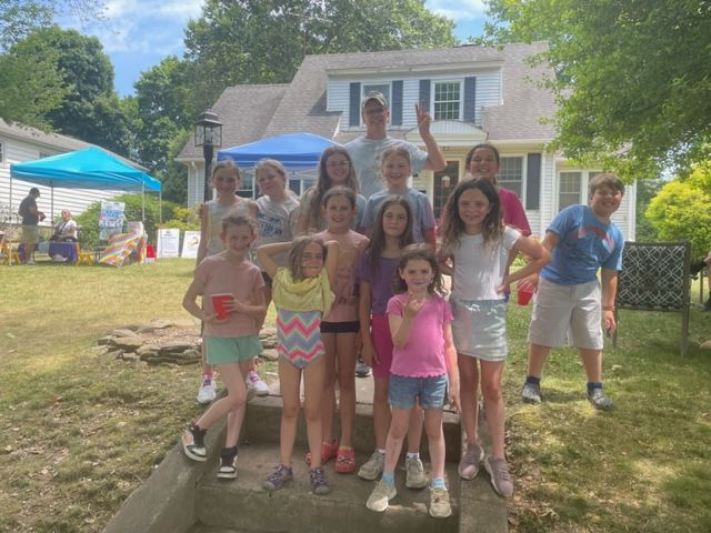 A group of children are posing for a picture in front of a house.