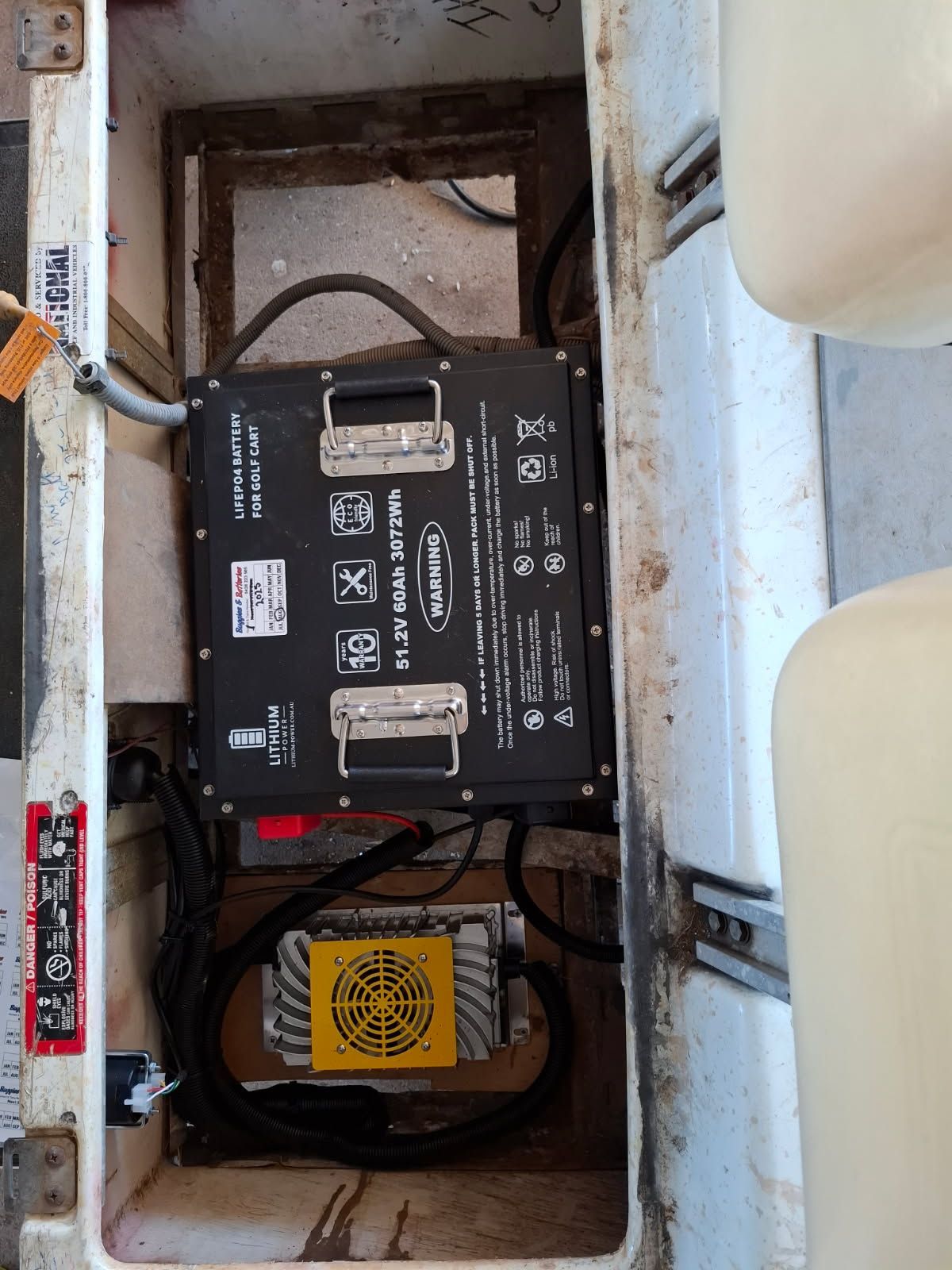Black Battery and Yellow Charger in White Compartment — Buggies & Batteries in Gladstone, QLD