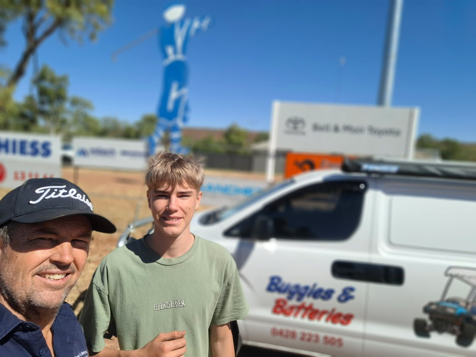Father and son infront of a White Van is Parked on the Side of a Road  — Buggies & Batteries in Hidden Valley, QLD