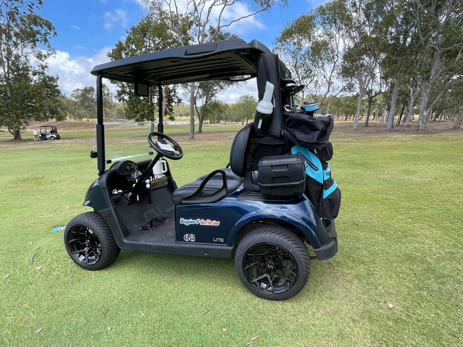 Dark Blue Golf Cart on Green Grass With Golf Bag — Buggies & Batteries in Emerald, QLD