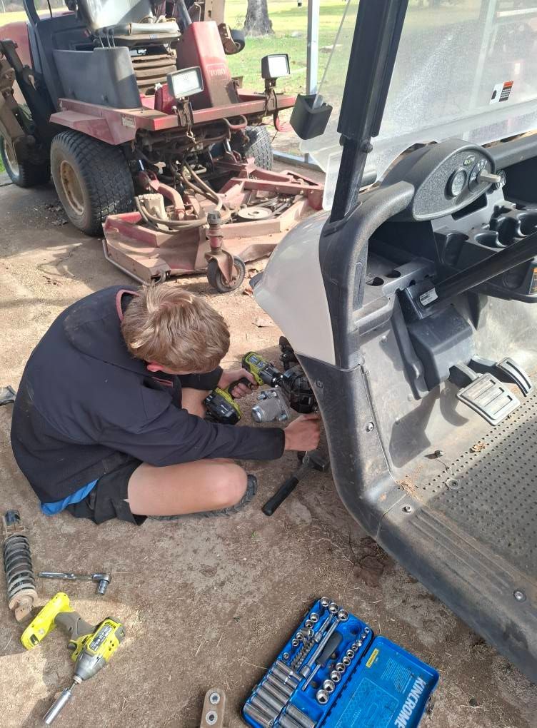 Person Repairs a Golf Cart Outside — Buggies & Batteries in Emerald, QLD