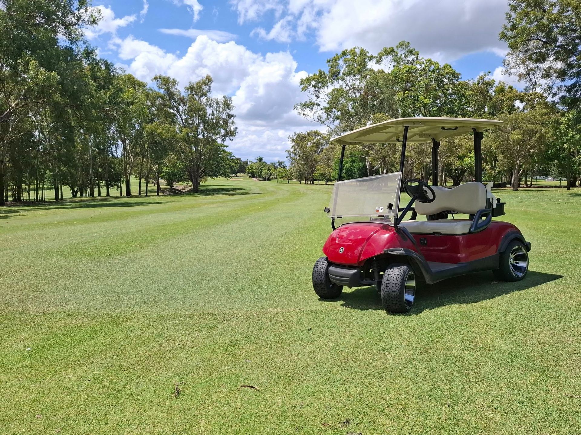 Red Golf Cart Parked on a Green Golf Course — Buggies & Batteries in Hidden Valley, QLD