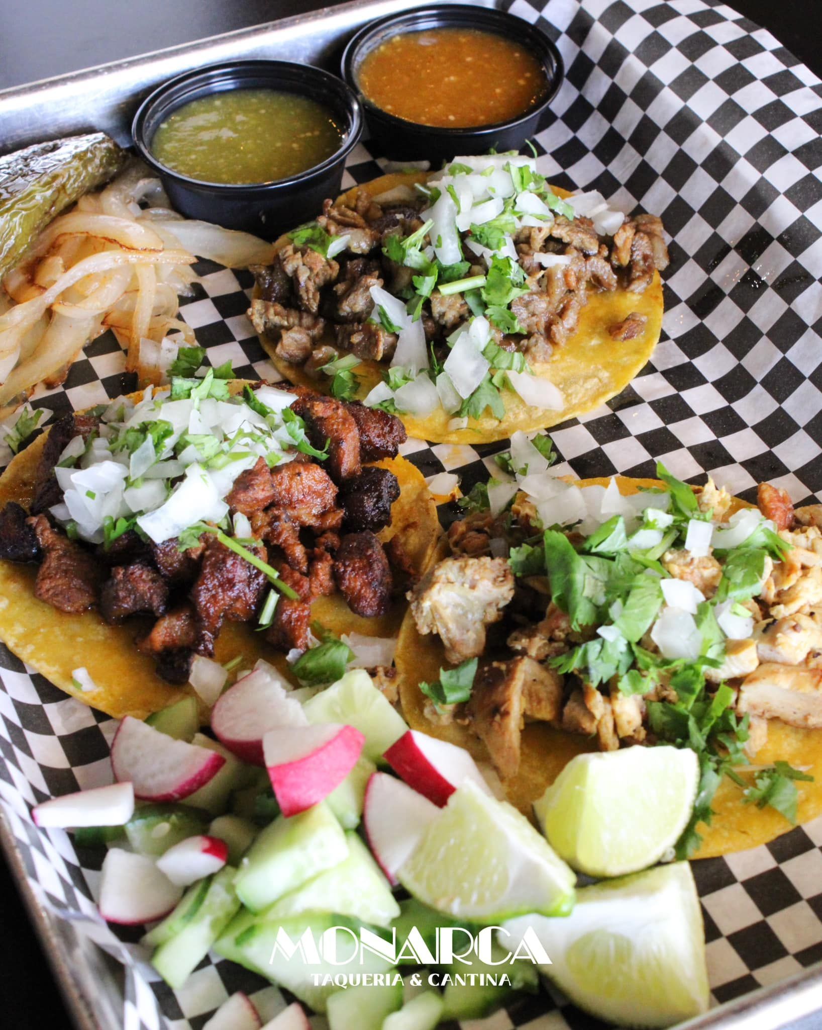 A tray of tacos and vegetables on a checkered napkin.