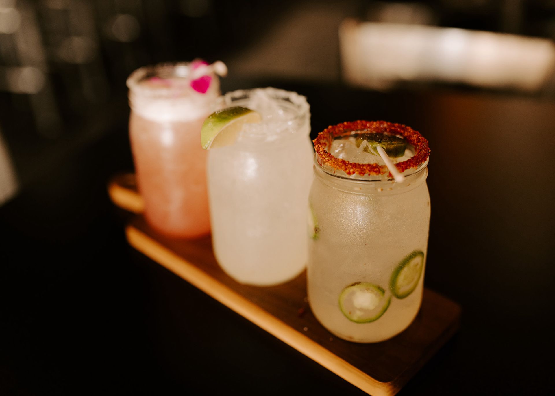 Three different types of drinks are sitting on a wooden tray.