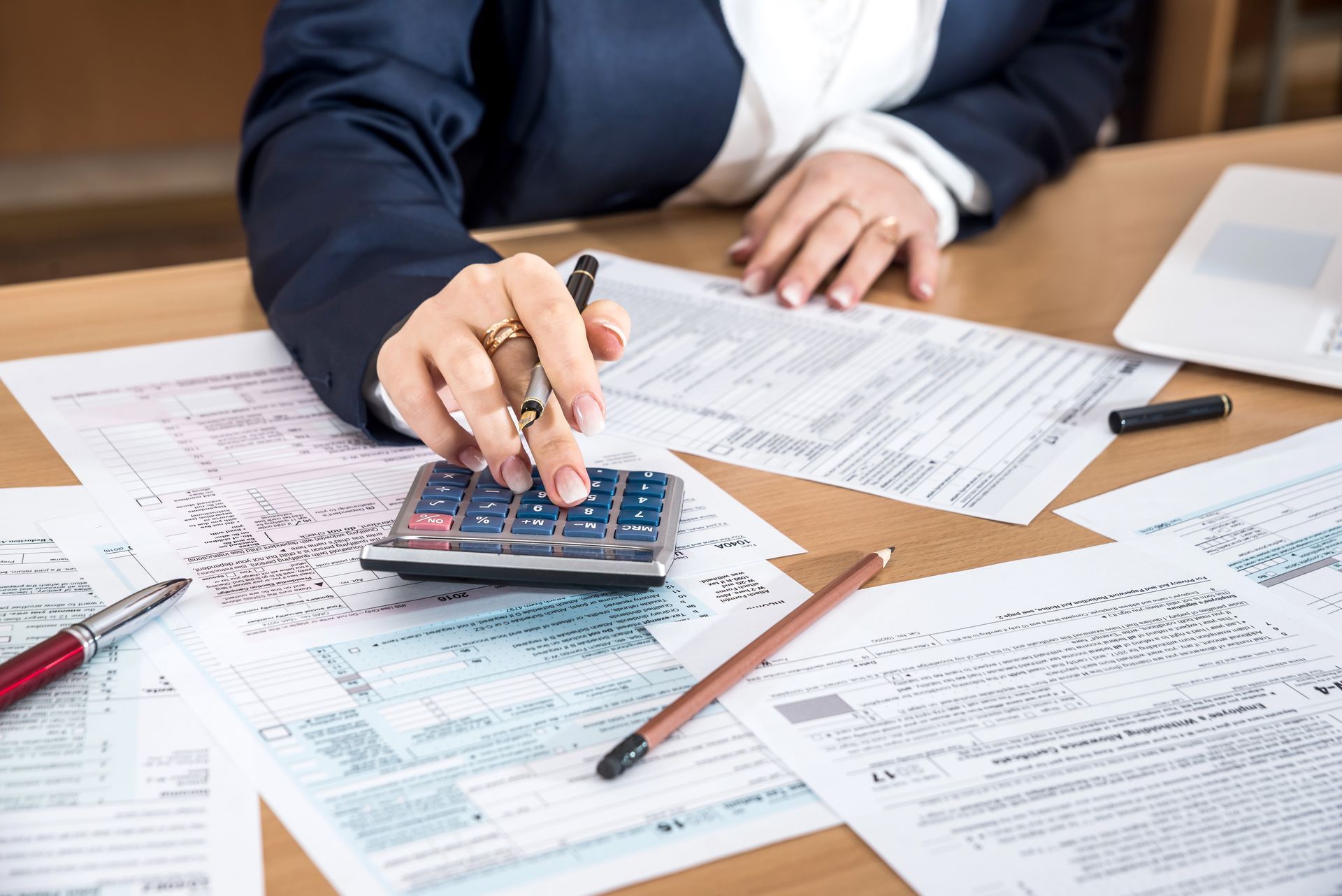 A woman is sitting at a desk using a calculator.