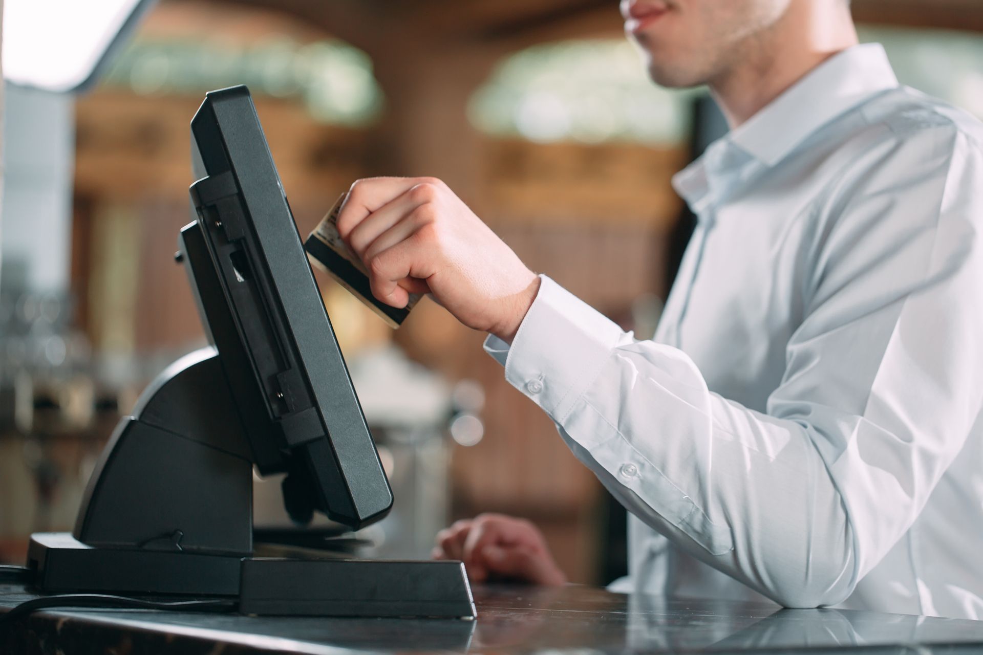 Person swiping a credit card on a point-of-sale system at a counter.