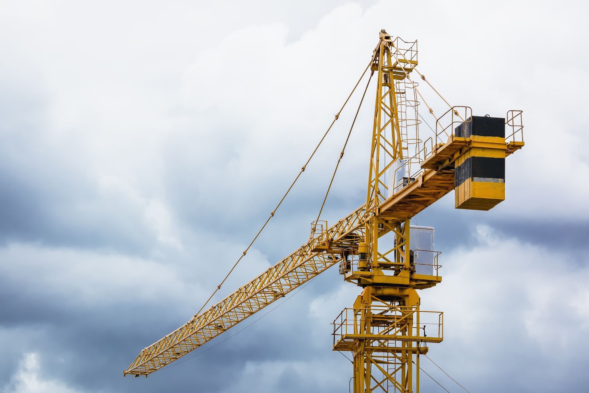 A yellow construction crane is against a cloudy sky.
