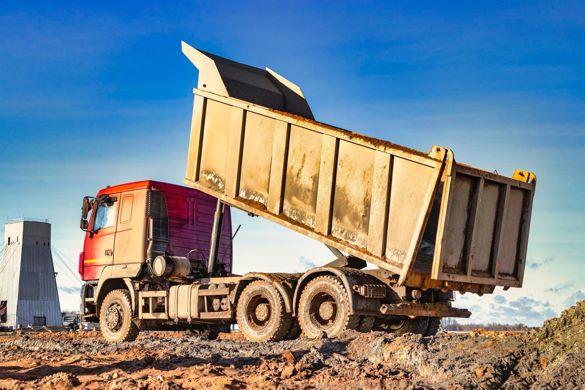 A dump truck is driving through a dirt field.