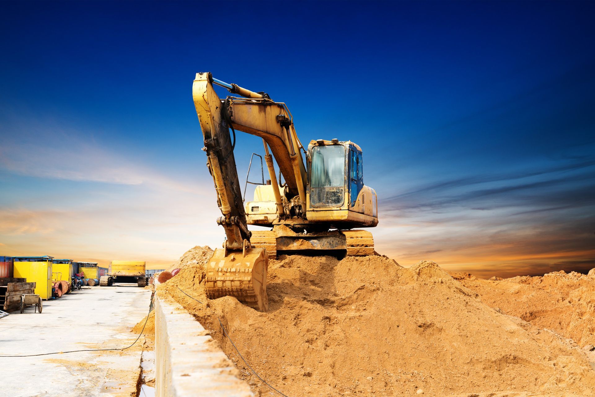 A yellow excavator is digging a hole in the dirt at a construction site.