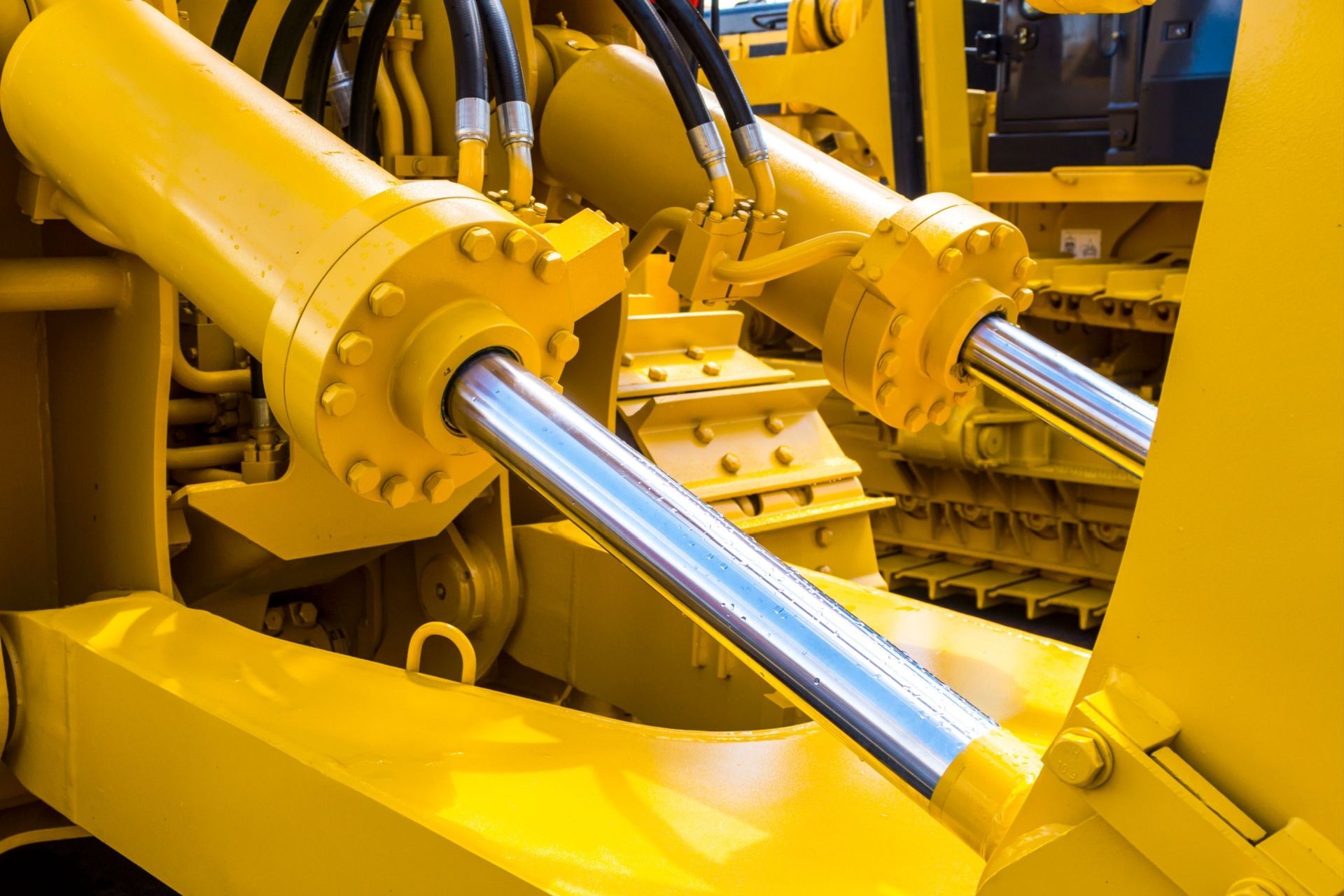 A close up of a yellow hydraulic cylinder on a bulldozer.