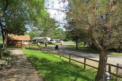 A dirt path leading to a campground with a wooden fence and trees.