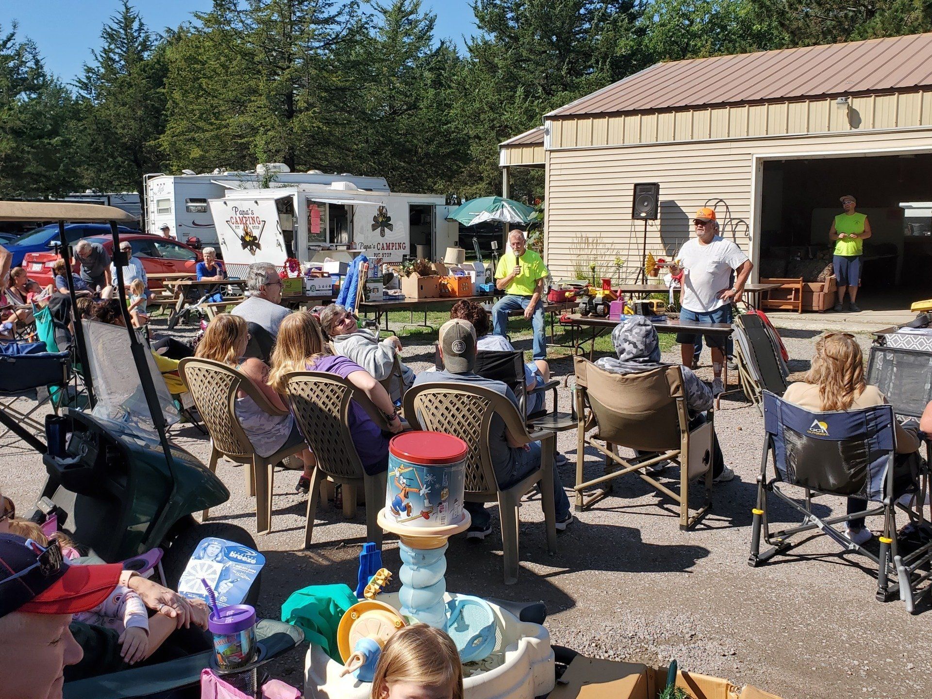 A group of people are sitting in chairs in front of a garage.