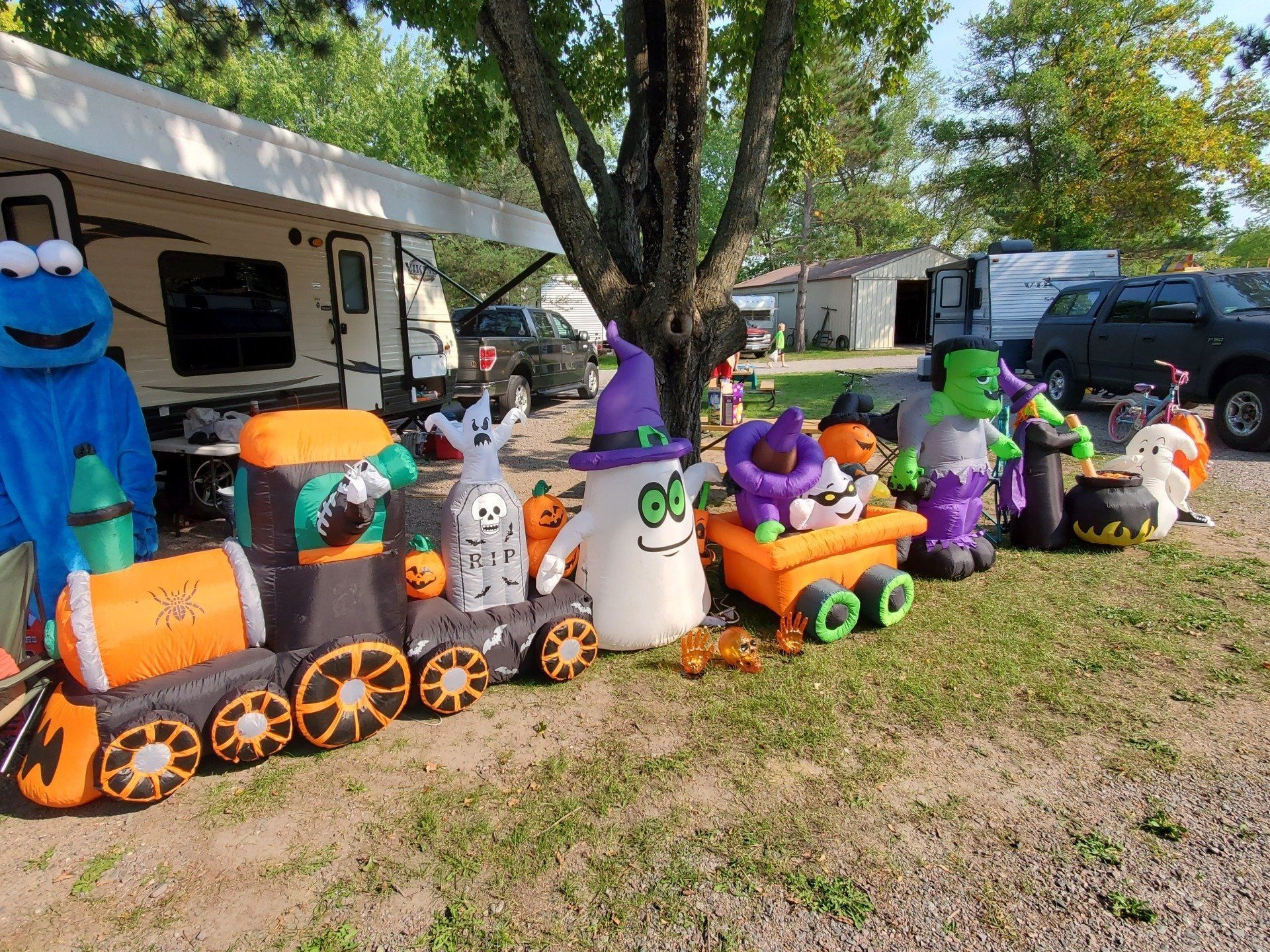A row of halloween decorations are lined up in front of a rv.
