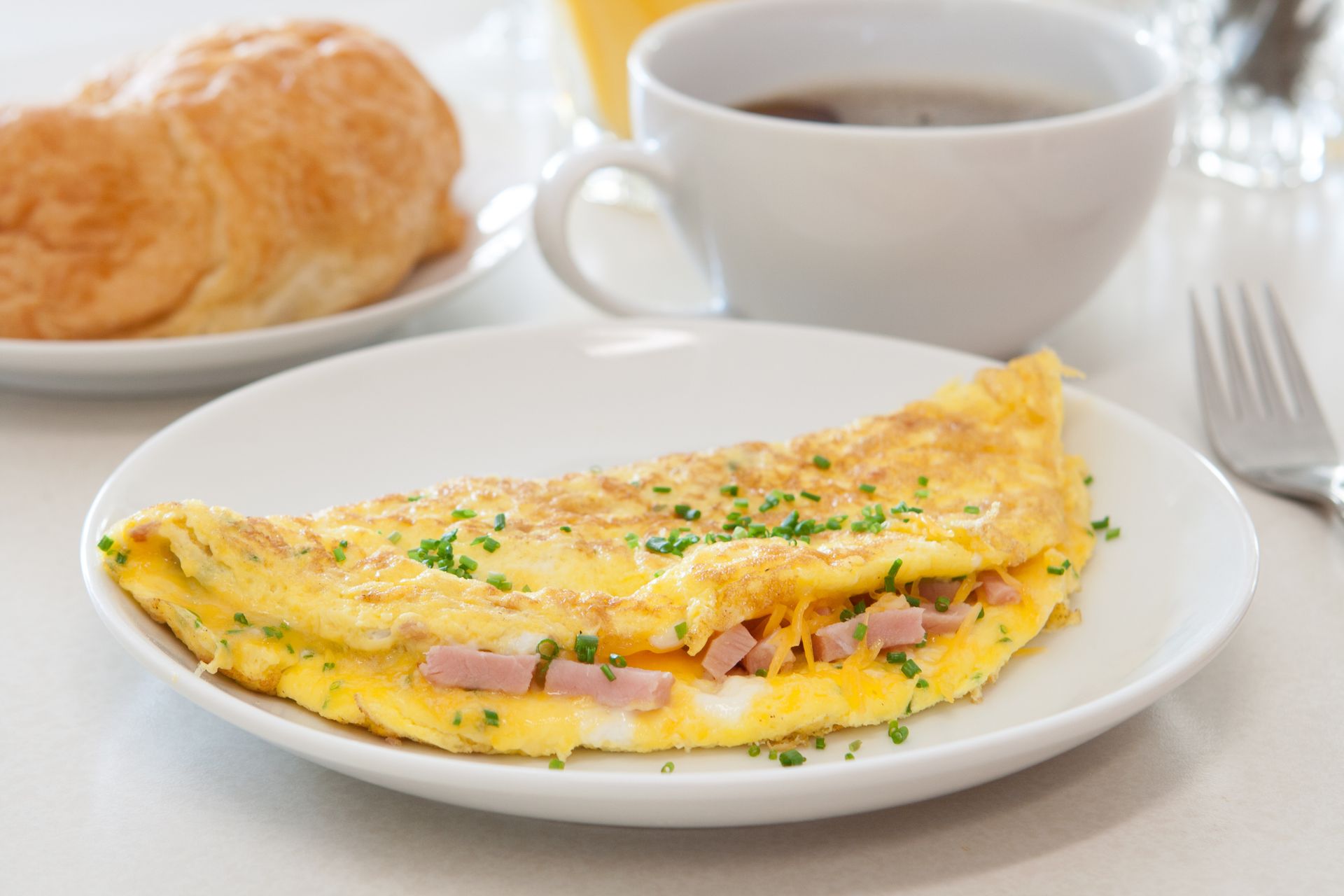 A white plate topped with an omelet and a cup of coffee.