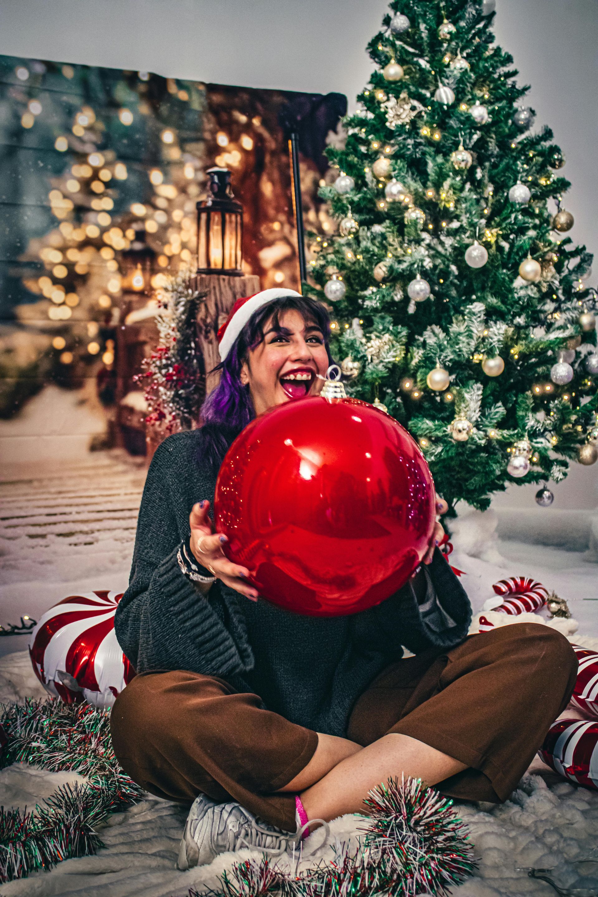 Lady holding a large red shiny Christmas tress bulb