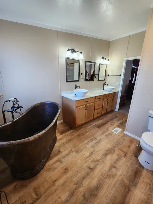 A bathroom with a tub , sinks , mirrors and a toilet.