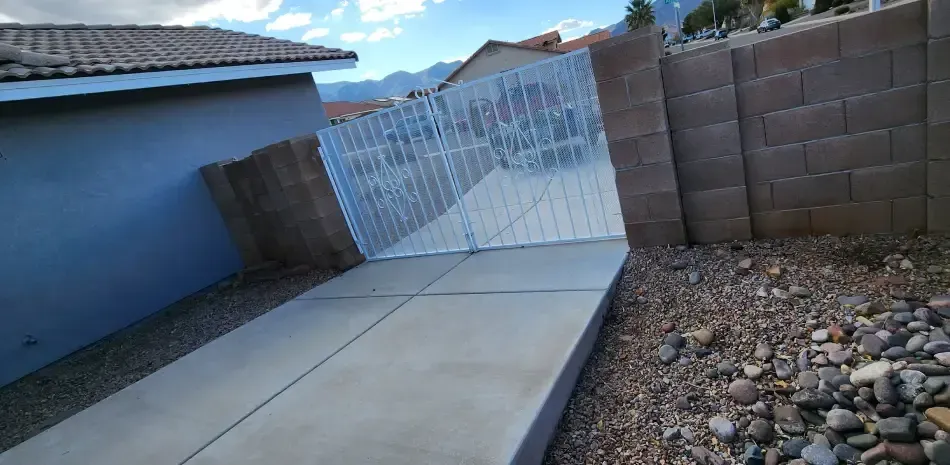 A concrete walkway leading to a brick wall and a house.