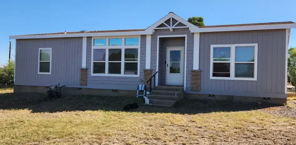A mobile home is sitting in the middle of a grassy field.
