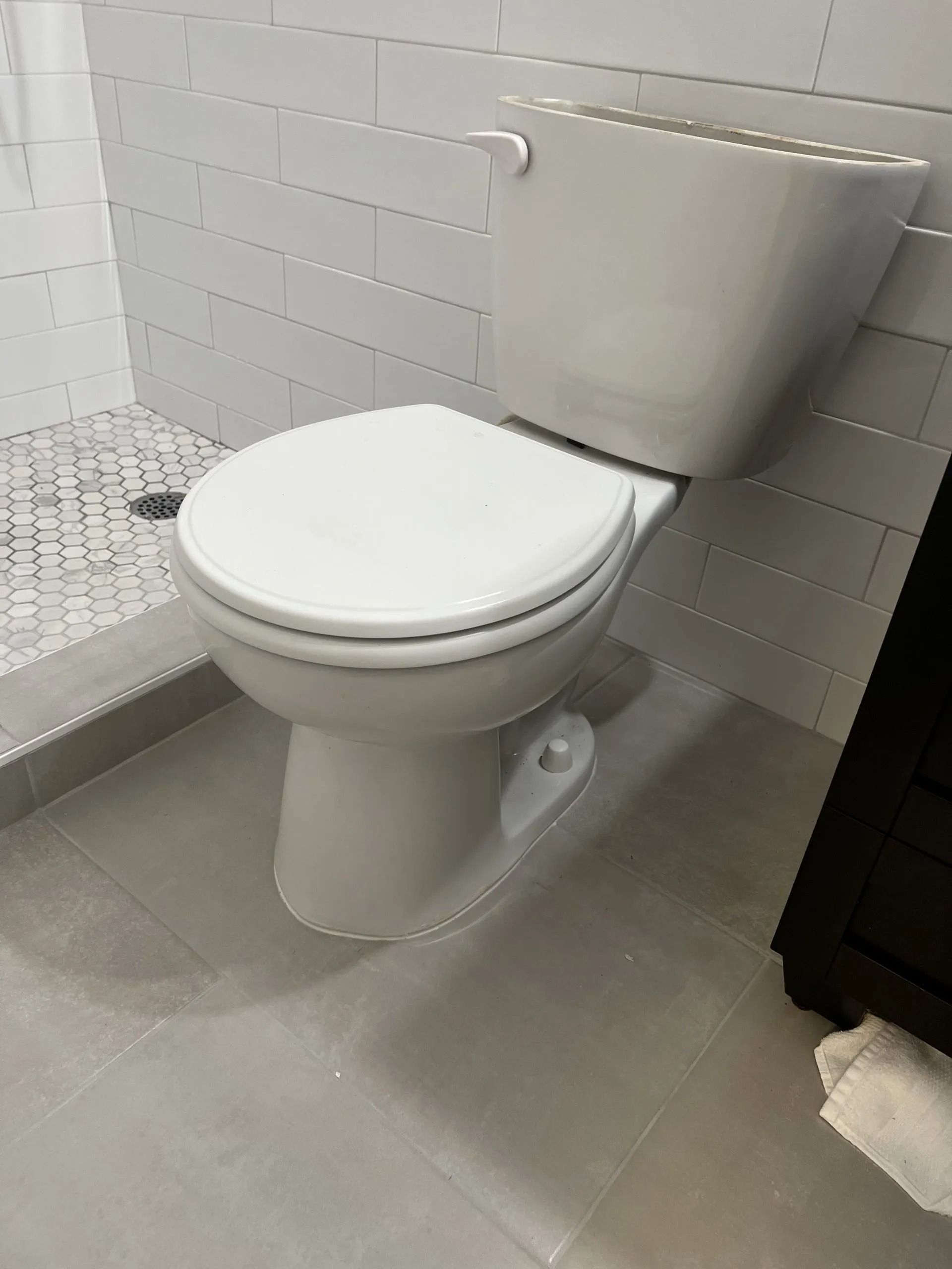 White toilet in a modern bathroom with grey tiled walls and floor.