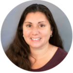 Woman with long brown hair, smiling, wearing a dark red shirt, set in a circular frame.