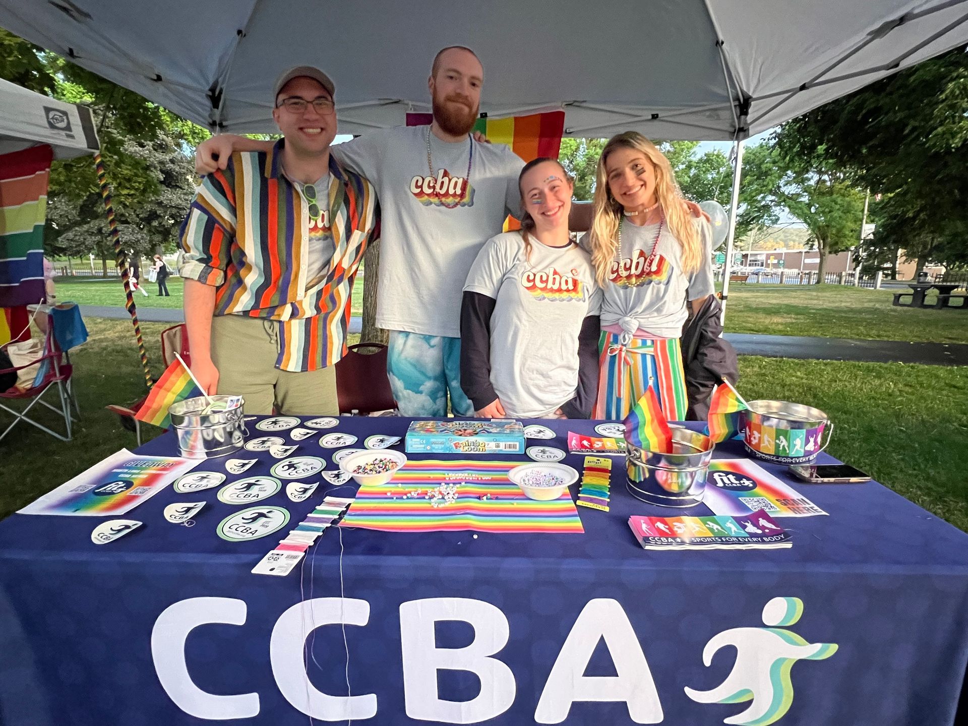 People at a pride booth with rainbow flags and merchandise.