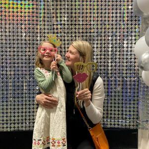 Woman and child posing for photo with props in front of a shiny background.