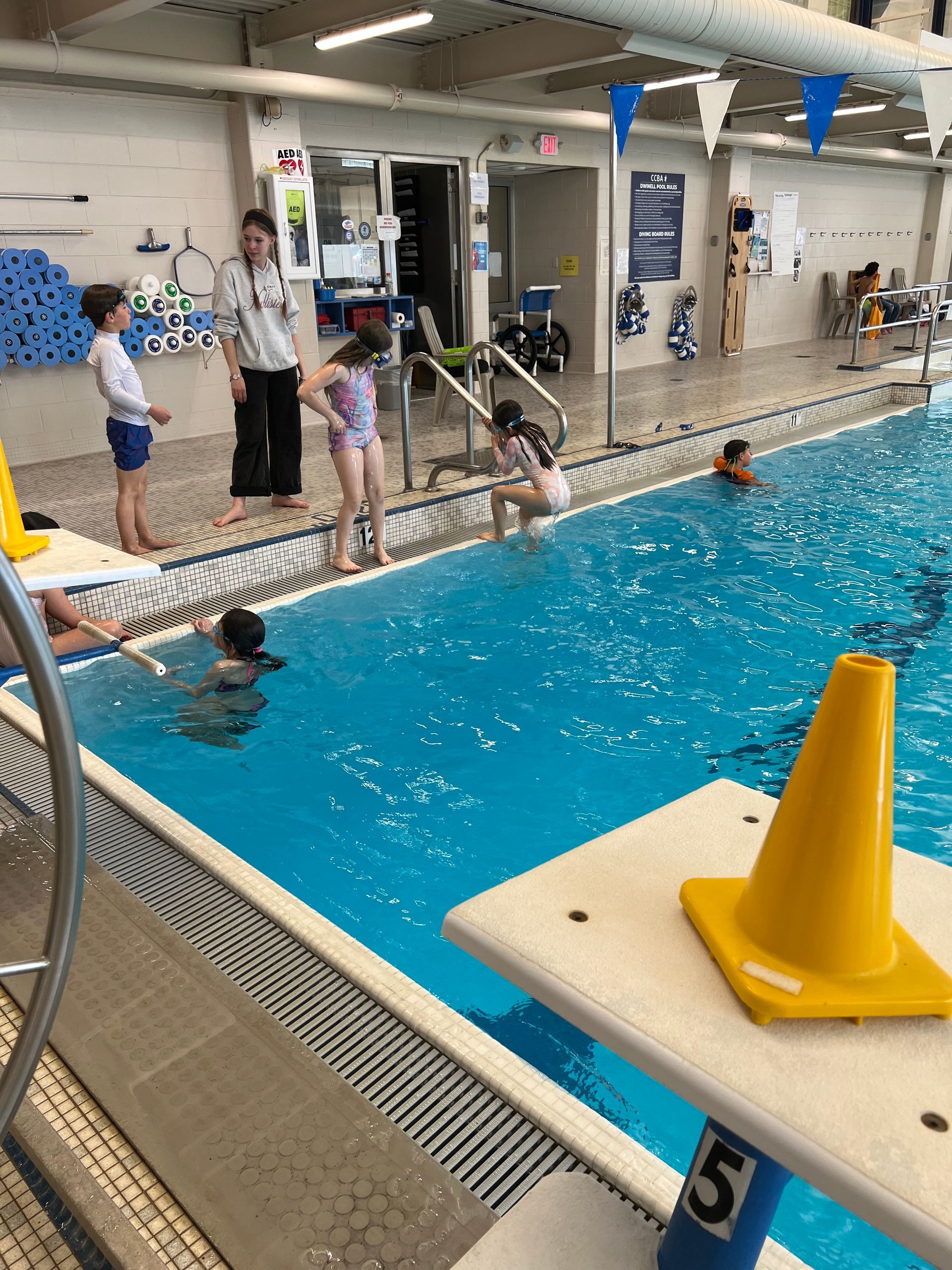 Swimmer in blue trunks, gliding underwater in a pool. White and blue lane markers visible.