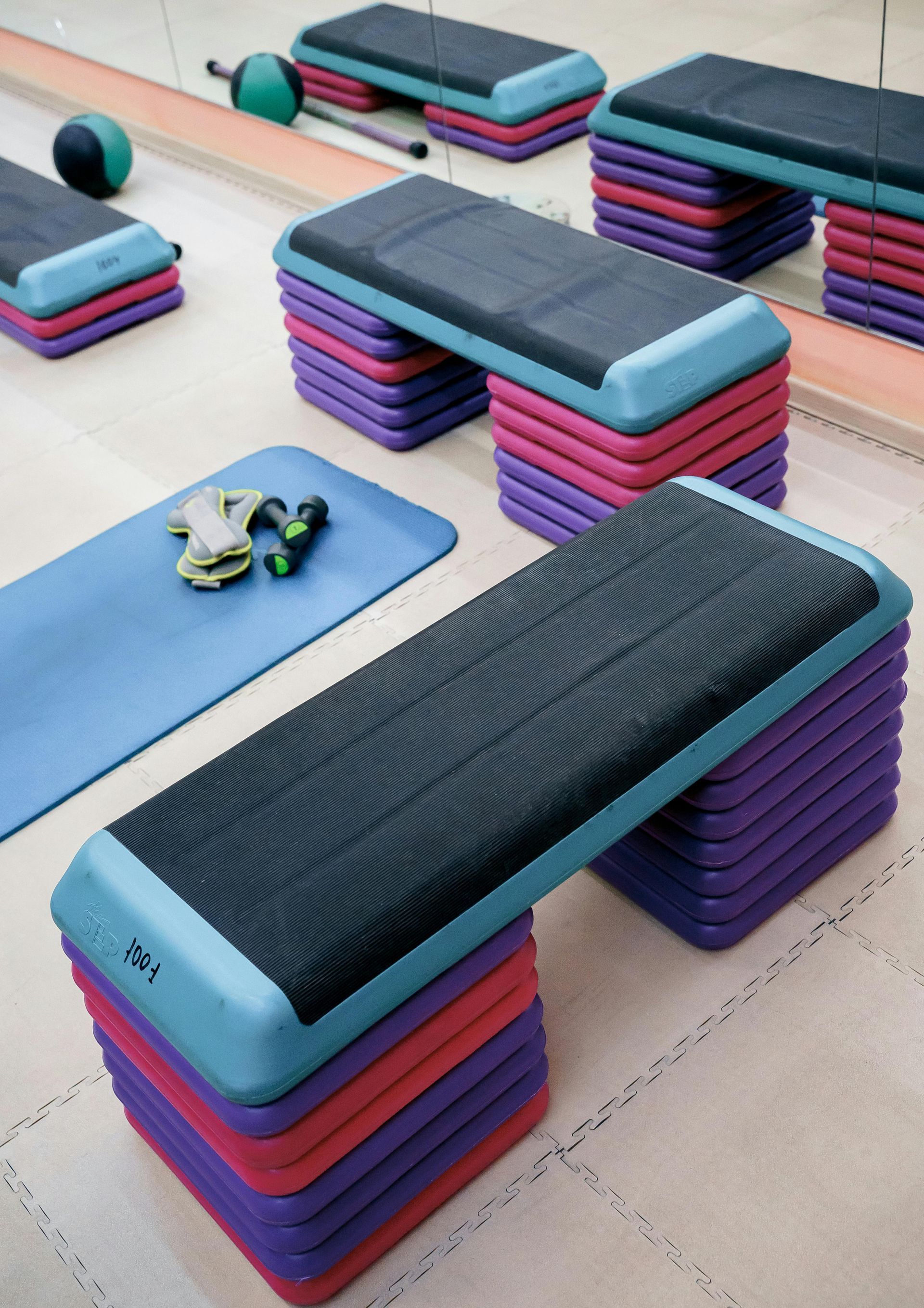 Fitness steps in a gym, with colorful risers and a yoga mat, ready for exercise.