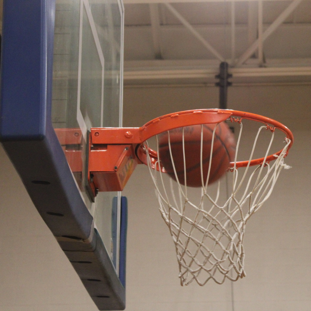 Basketball going through a hoop, indoors.