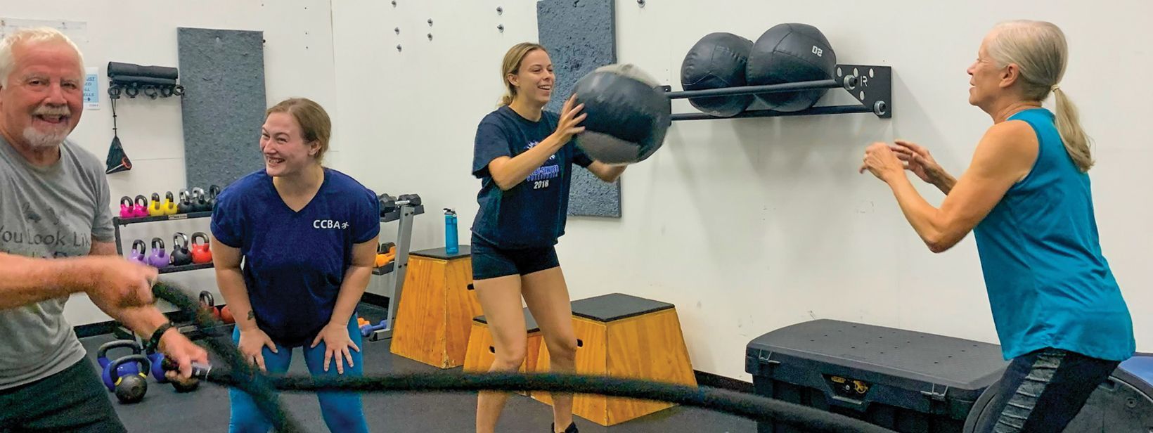 Woman doing battle rope exercises in a gym, wearing black shorts and top.