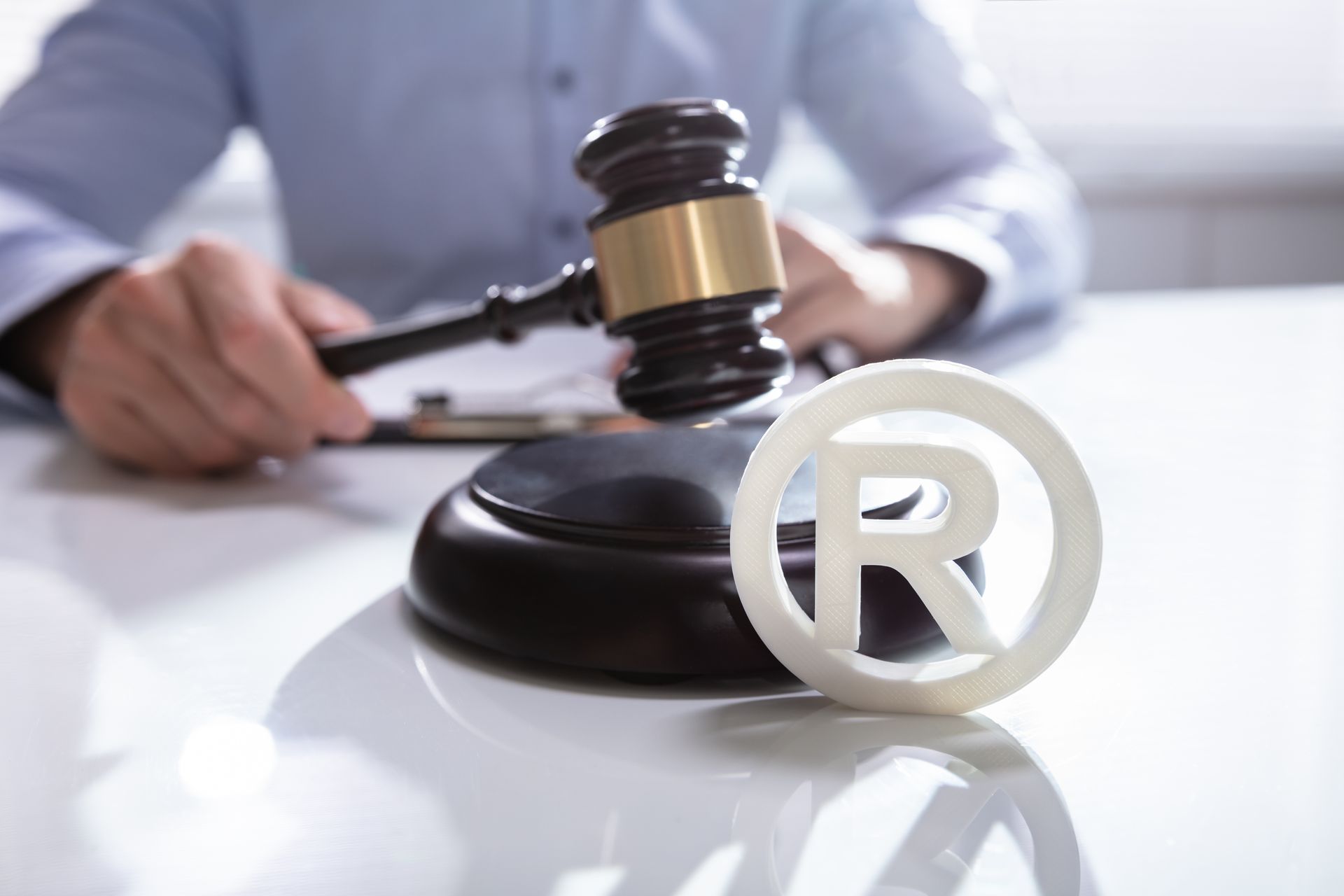 Registered trademark symbol and attorney holding gavel.