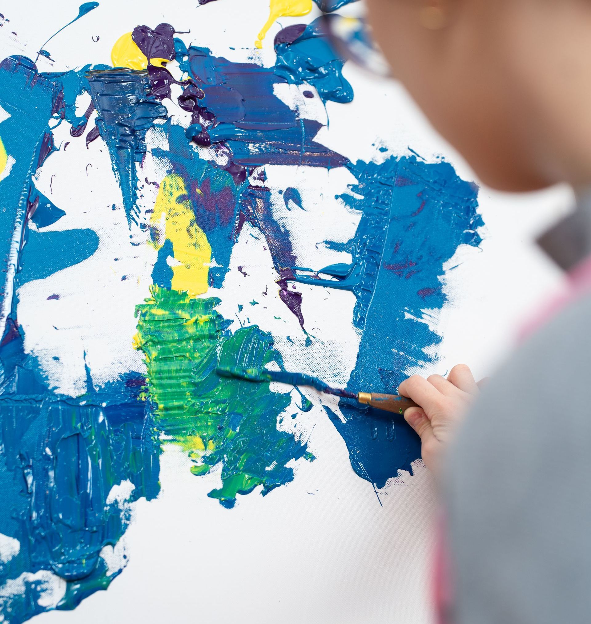 A person is painting a picture with blue and yellow paint