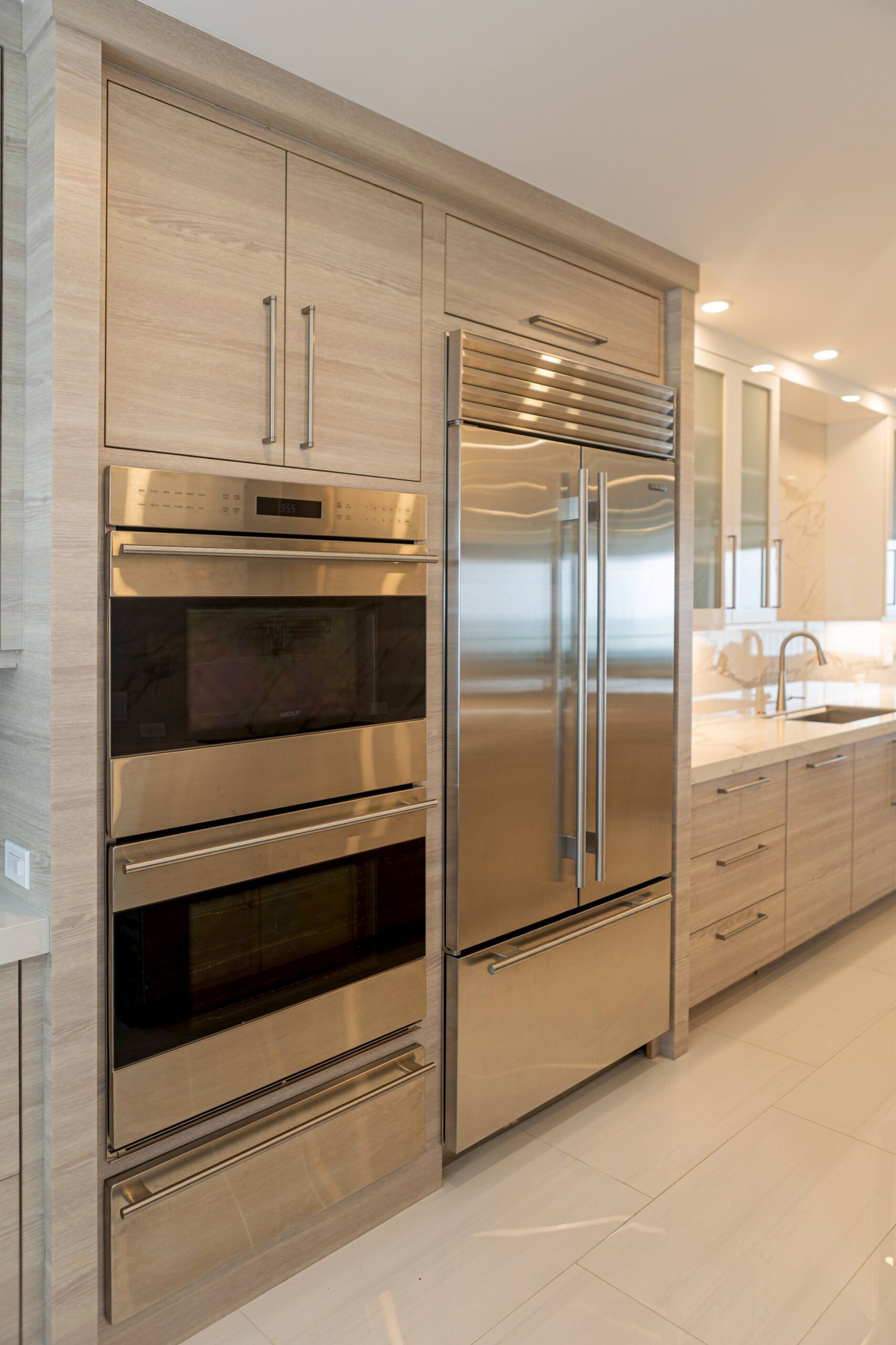 Stainless steel appliances built into light wood kitchen cabinetry.