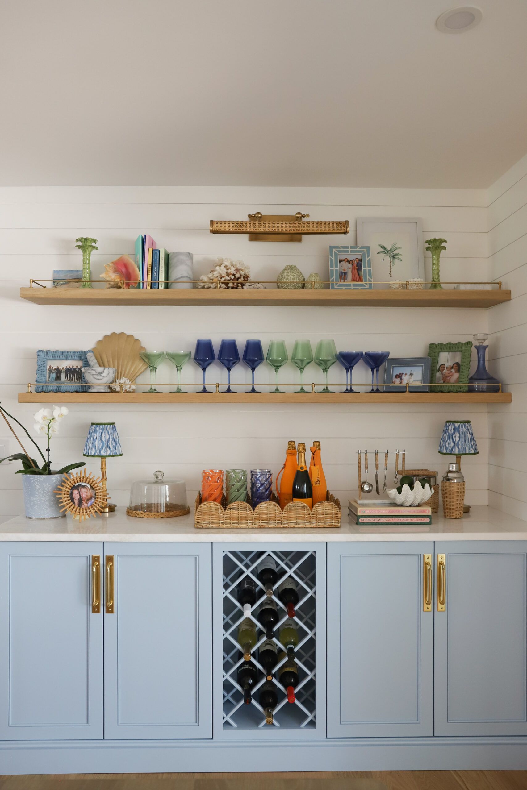 Light blue built-in bar with shelves, displaying glassware, decor, and wine bottles.