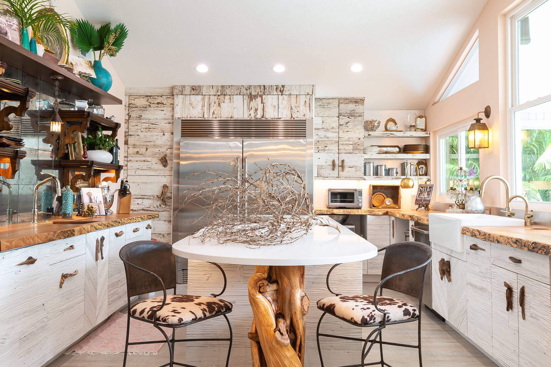 Kitchen with white cabinets, wood accents, and a central table with two cow-print stools.