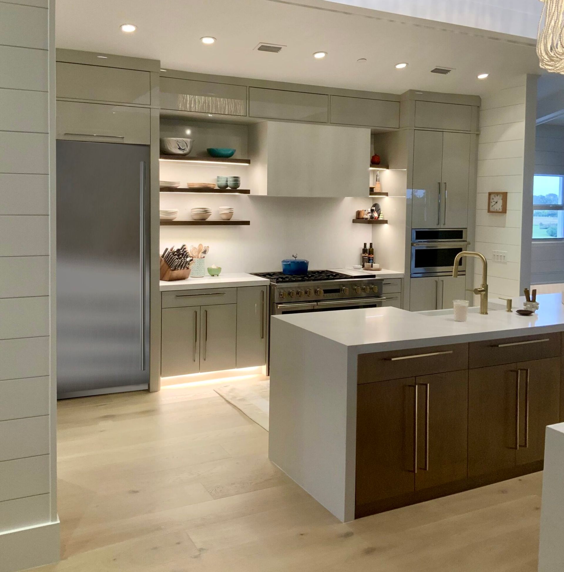Modern kitchen with gray cabinets, white countertops, stainless steel appliances, and a central island.