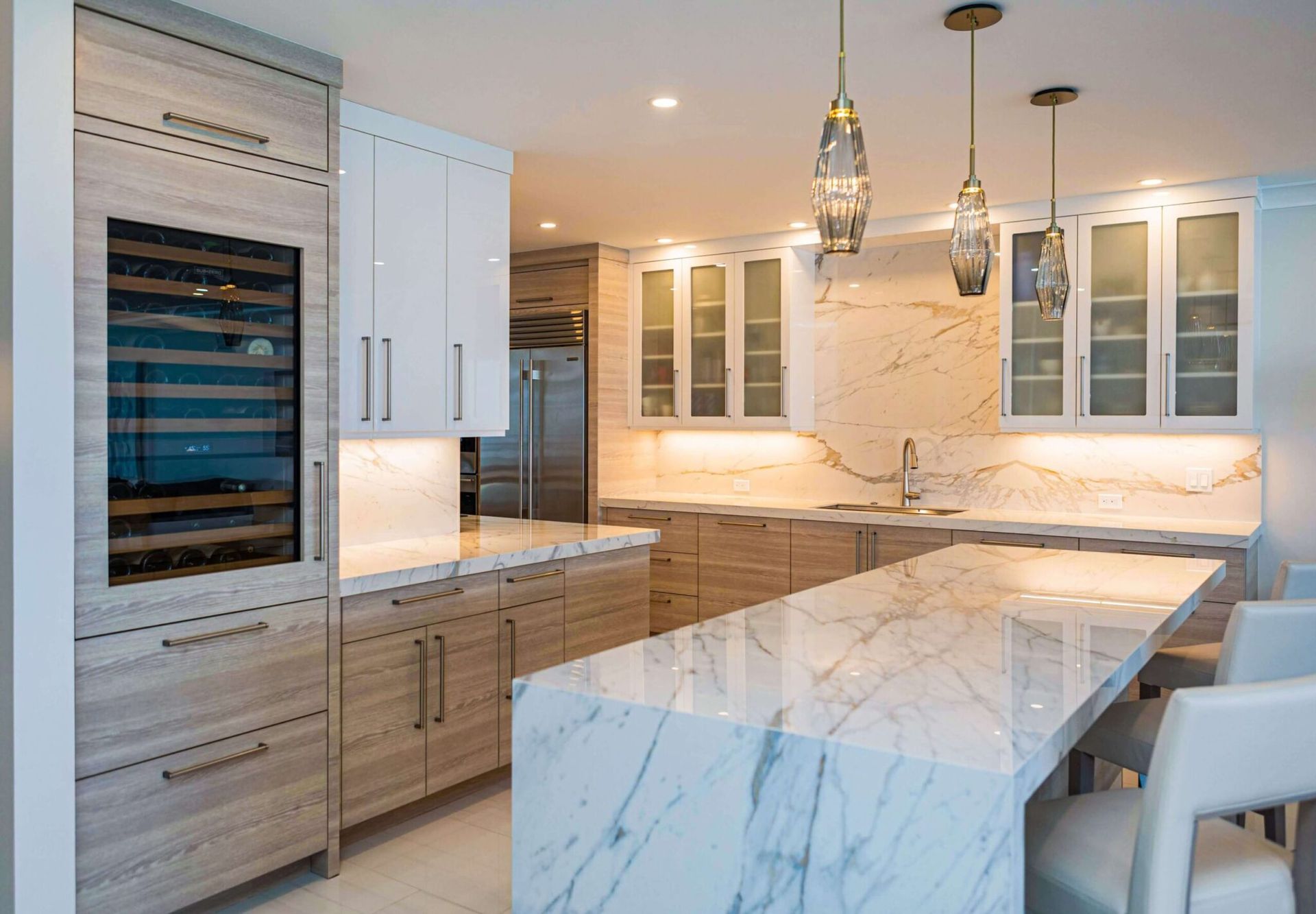 Modern kitchen with marble countertops, wood cabinets, and two pendant lights.