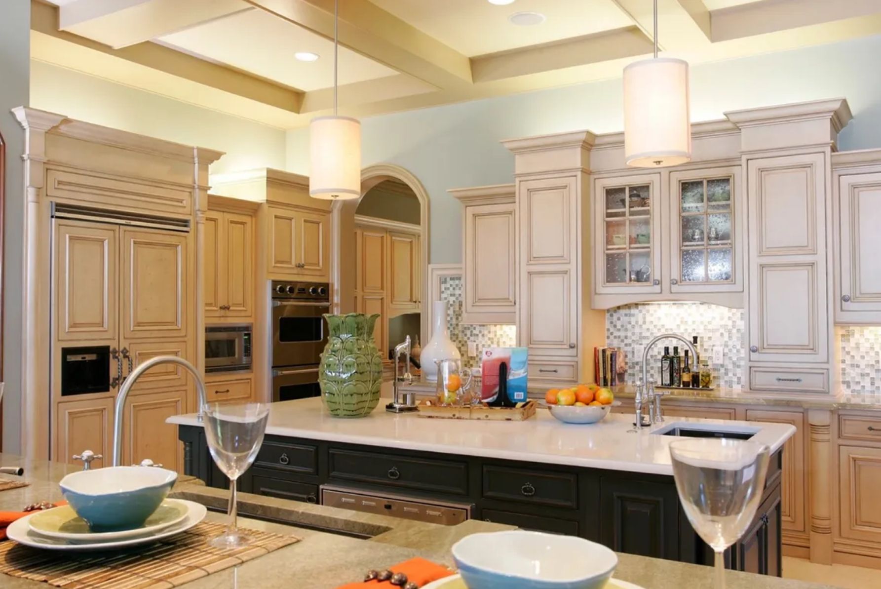 Elegant kitchen with light-colored cabinets, a dark island, and pendant lights.