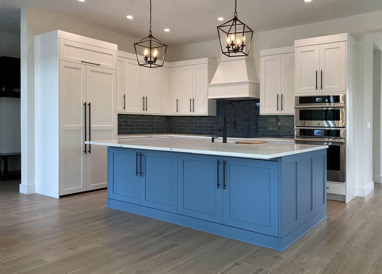 Modern kitchen with white and blue cabinets, island, and pendant lights.
