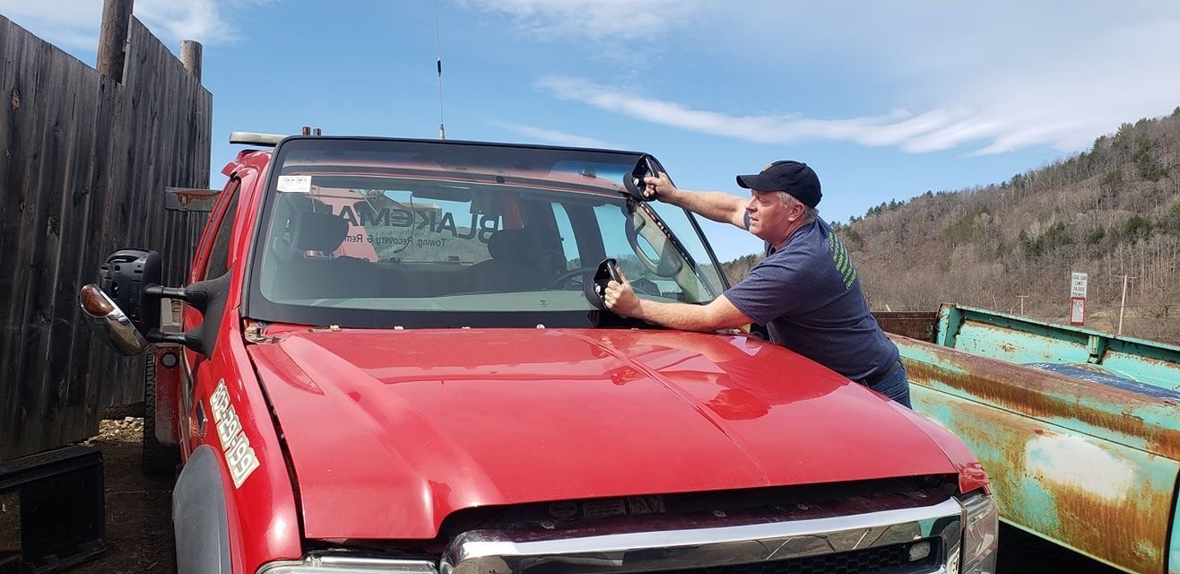 A man is installing a windshield on a red truck.